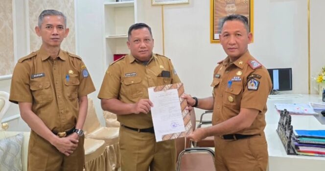 
 Sekda Amir Hasan saat menyerahkan SK plt Kepala Dinas Perpustakaan dan Arsip Kota Kendari kepada Akrim Kurdin. Foto Kadamu/Kolaka Pos